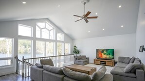Amplia sala de estar con un ventanal grande, ventilador de techo y televisor de pantalla plana.