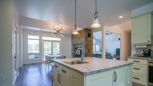Una cocina moderna con una isla grande, electrodomésticos integrados y una chimenea de piedra.