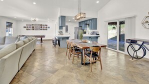 A spacious living area with a dining table, sofa, and kitchen area.