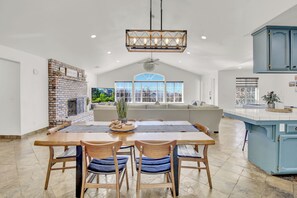 A spacious kitchen with a large island, a brick fireplace, and a view of the outdoors. - Villa near Yosemite & bass lake Hot Tub EVcharge (Oakhurst)