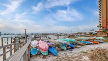 A pier with kayaks lined up, a marina in the background, and a tall building to the right.