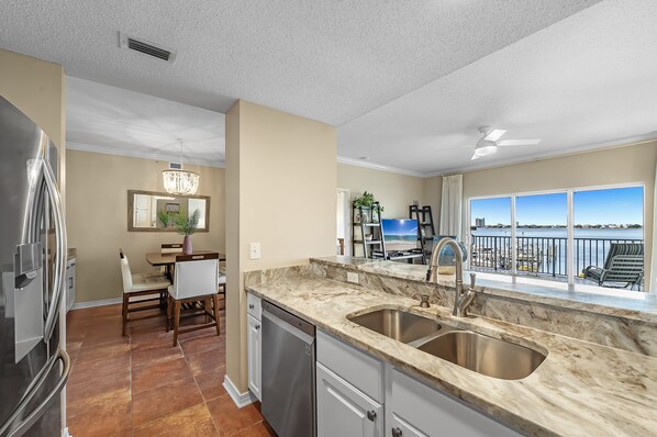 A modern kitchen with a large window, a dining area, and a view of the ocean. - South Harbour 2D | Sunset Views | Pensacola Beach | My Beach Getaways (Pensacola Beach)