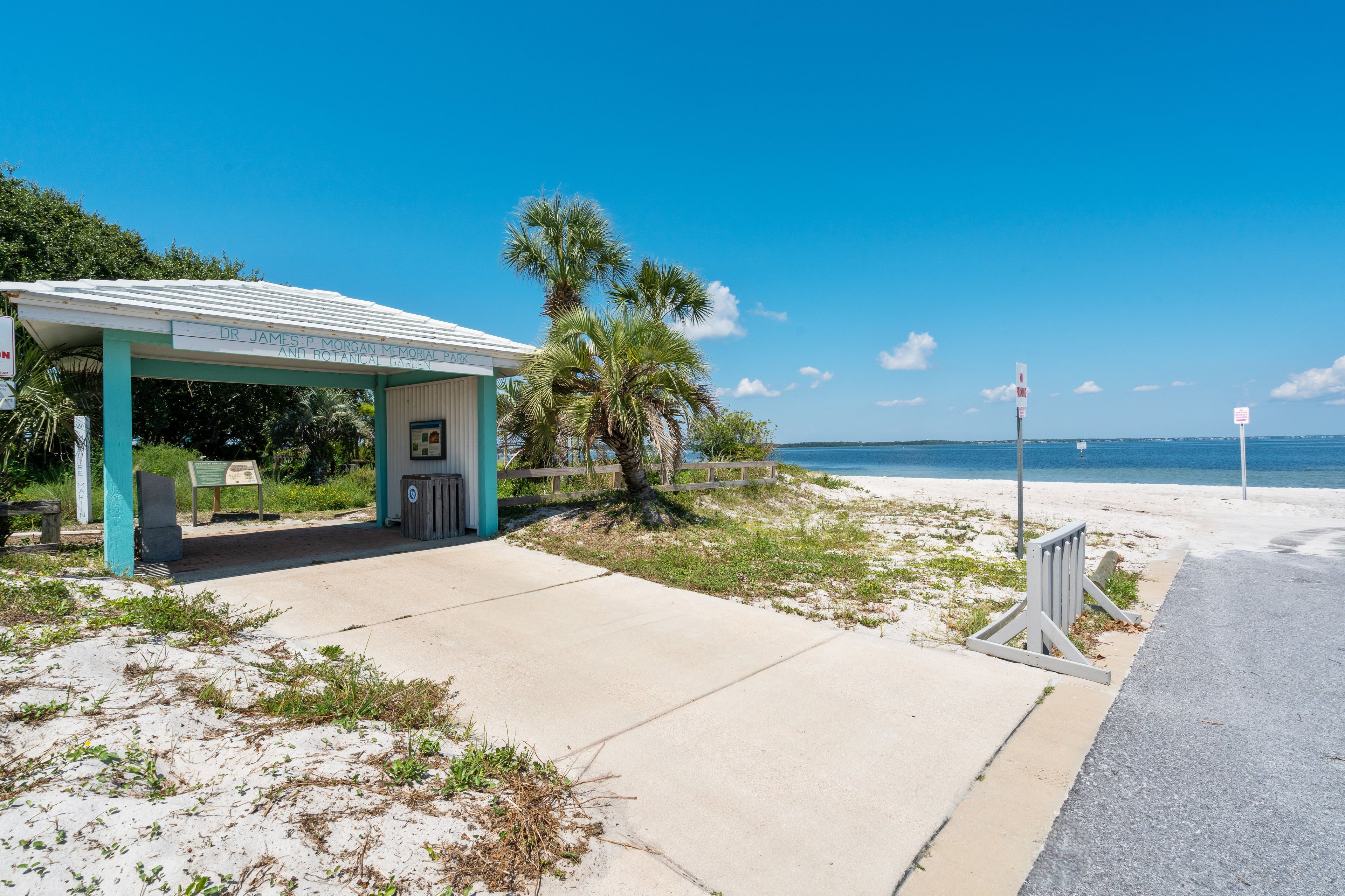 A beachside park with a covered pavilion, a trash bin, and a clear view of the ocean.