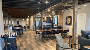 A spacious, modern interior with a long dining table, comfortable seating, and a chessboard. - Modern Luxury Meets Historic Charm: Unwind in Style in Purpose Executive Suites (Pocatello)