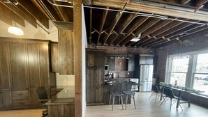 A spacious kitchen with wooden cabinets, a stainless steel refrigerator, and a large island with bar stools. - Modern Luxury Meets Historic Charm: Unwind in Style in Purpose Executive Suites (Pocatello)