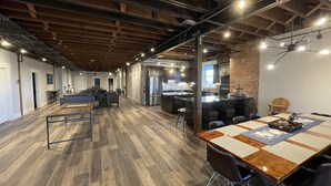 A spacious, modern kitchen with a large island, dark cabinetry, and a brick accent wall. - Modern Luxury Meets Historic Charm: Unwind in Style in Purpose Executive Suites (Pocatello)