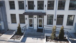 A building with a sign reading "PURPOSE CENTER" at the entrance, featuring a double door, a small set of stairs, and two potted plants on either side. - Modern Luxury Meets Historic Charm: Unwind in Style in Purpose Executive Suites (Pocatello)