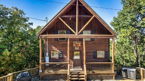 A wooden lodge with a front porch, a sign reading "Big Bear Lodge," and a small outdoor seating area. - Cabin With Amazing Mountain Views! Sleeps 8! 8 Mins From The Strip! (Sevierville)