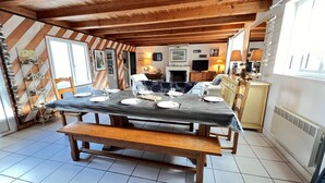 A dining area with a large table set for six, wooden benches, and a fireplace in the background. - Charming villa in the center with courtyard (LA COUARDE SUR MER)