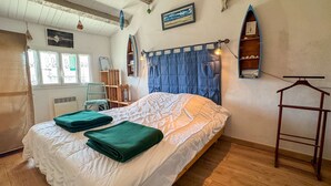 A bedroom with a bed, a chair, a wardrobe, and a window with curtains. - Charming villa in the center with courtyard (LA COUARDE SUR MER)