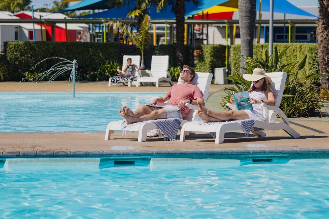 A pool area with lounge chairs and a water fountain.