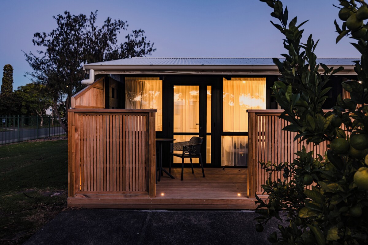 A wooden deck with a table and chairs, a sliding glass door, and a fenced area.