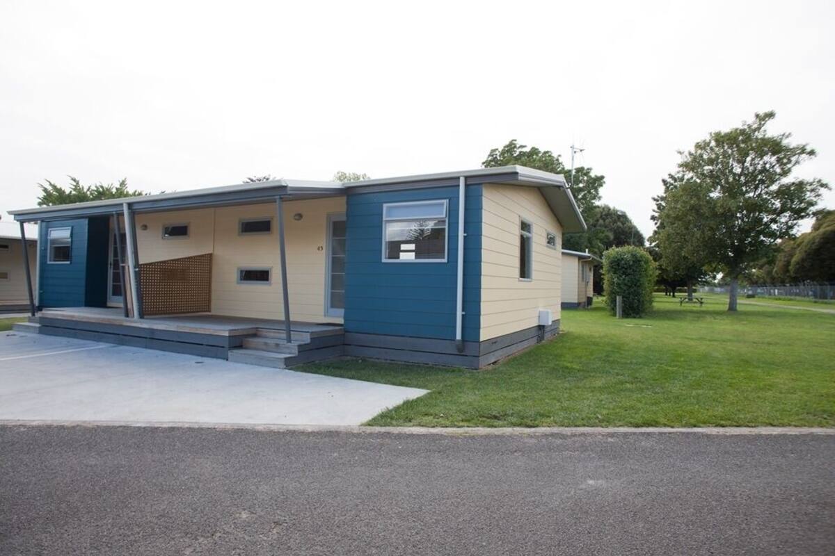 A mobile home with a covered porch, a small front yard, and a paved driveway.