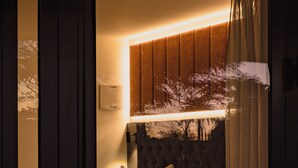 A bedroom with a bed, a nightstand, and a headboard with a light. - Kennedy Park Resort (Napier)