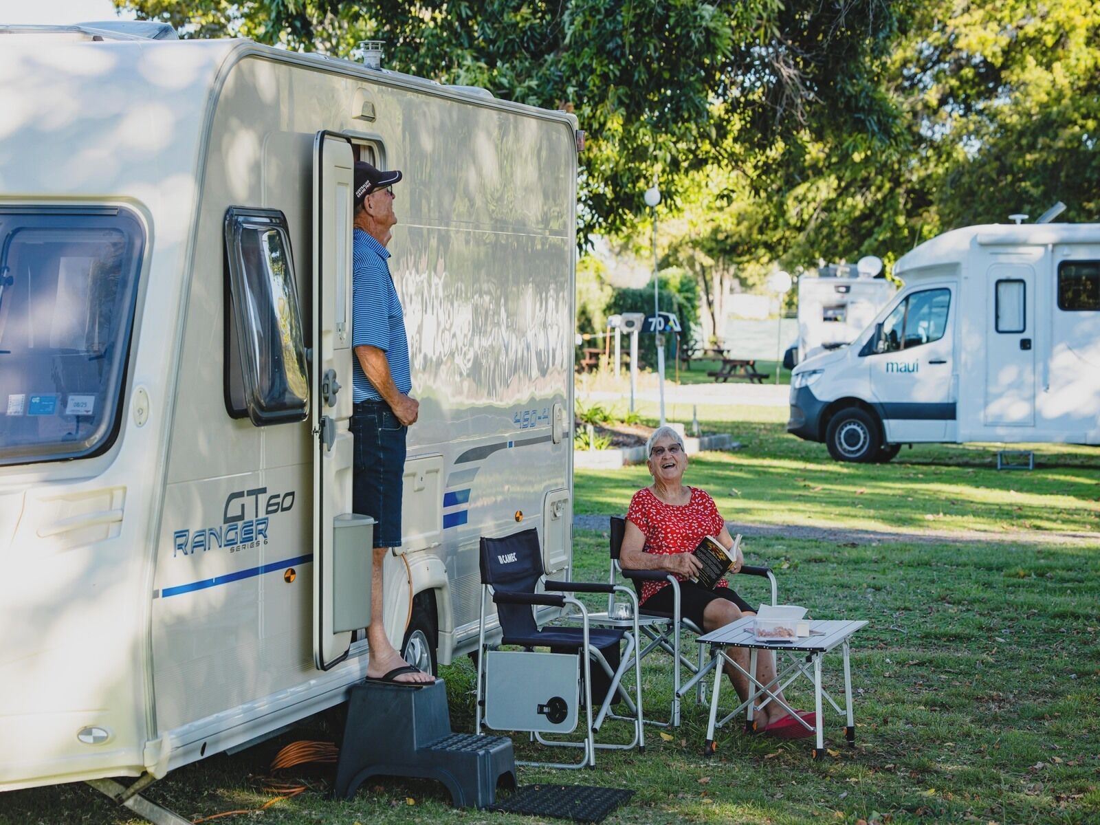 Van camper com um banquinho e uma mesa de jantar montada do lado de fora.