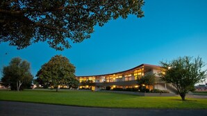 A modern building with a curved roofline, surrounded by well-maintained lawns and trees. - Kennedy Park Resort (Napier)