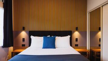Una habitación de hotel con una cama grande, un cabecero de madera y una pared con listones verticales.