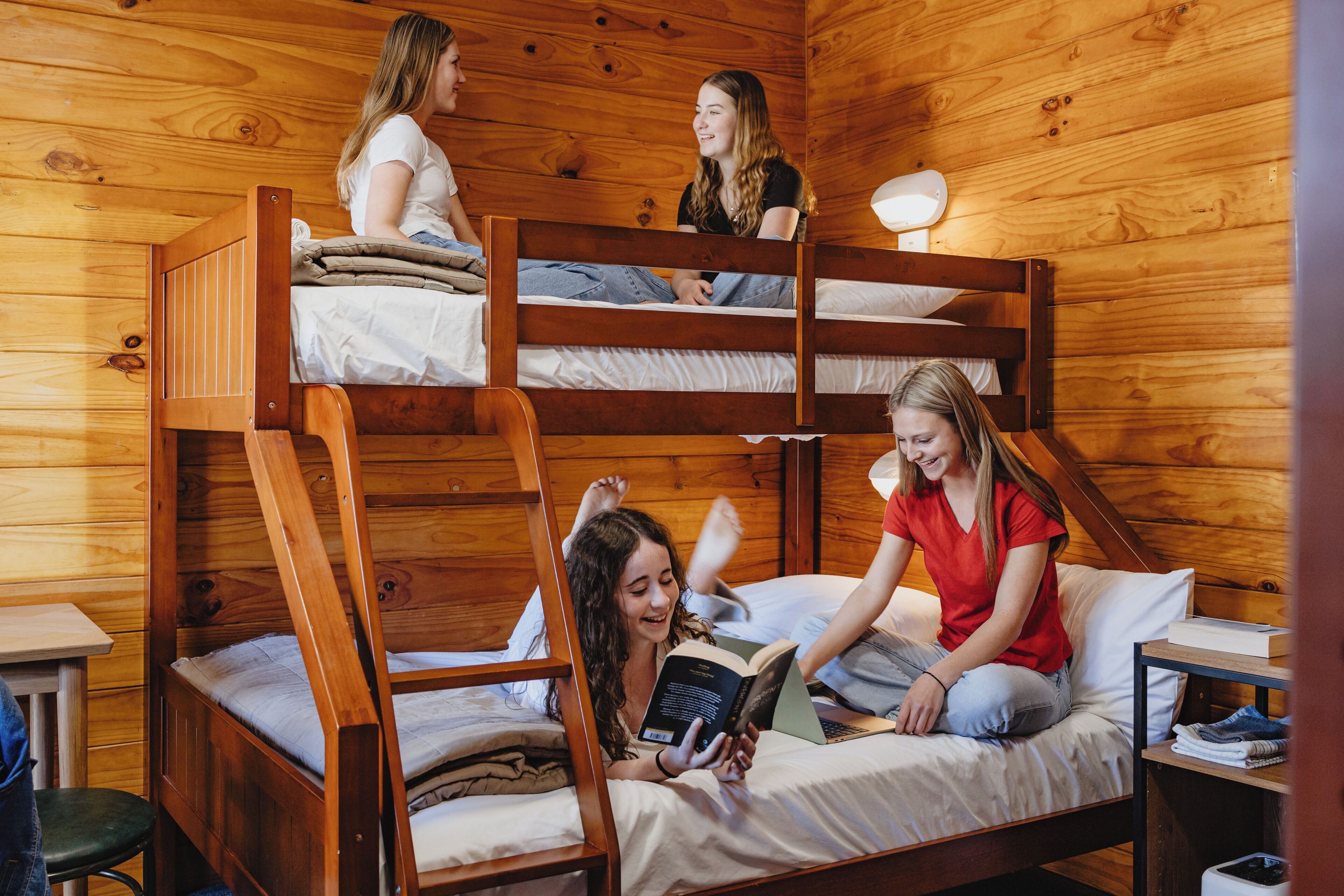 Une chambre avec des lits superposés, des murs en bois et une petite table avec une lampe.