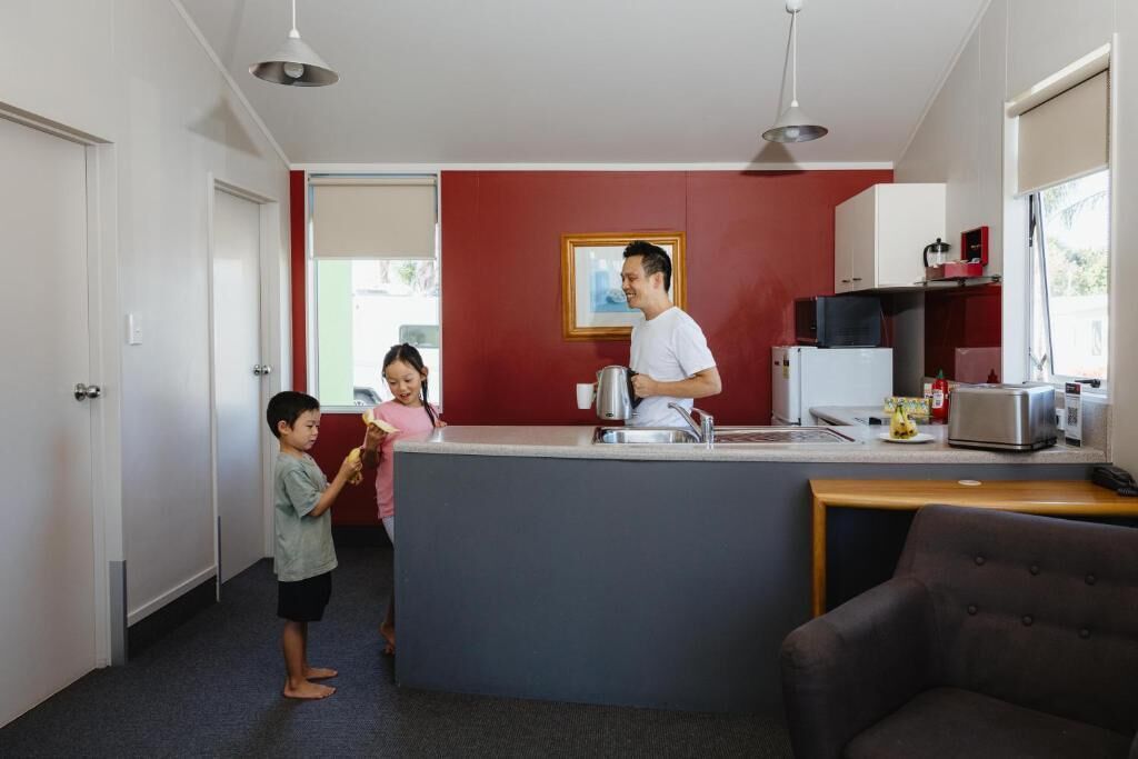 A compact kitchen with a central island, a dining area with a chair, and a red accent wall.