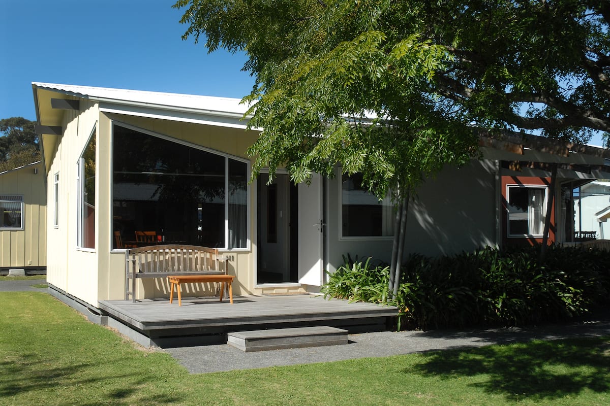 A modern house with a large glass window, a wooden deck, and a bench.