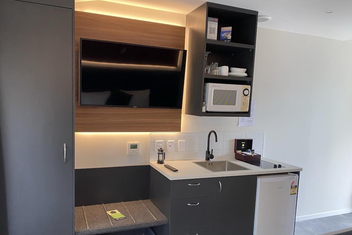 A compact kitchenette with a built-in microwave, a sink, and a small refrigerator.