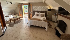 A bedroom with a large bed, a desk, a chair, a TV, and a window with curtains. - Pousada Flor de Lua Monte Verde (Camanducaia)
