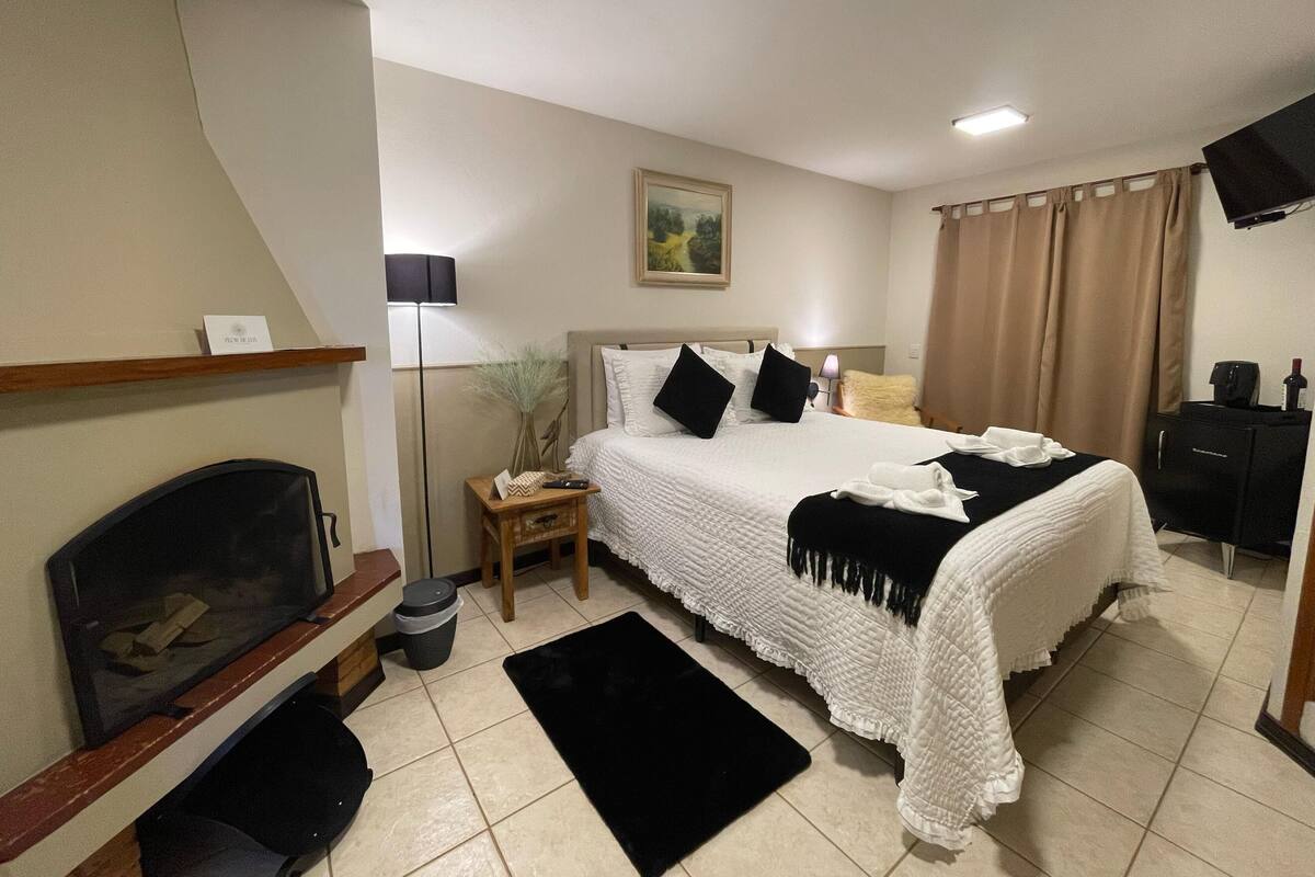 A bedroom with a bed, bedside table, lamp, TV, and a painting on the wall.