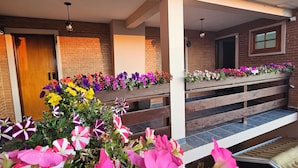 A covered outdoor area with a wooden bench and flower planters. - Pousada Flor de Lua Monte Verde (Camanducaia)