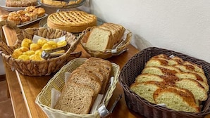 A buffet table with various breads and pastries. - Pousada Flor de Lua Monte Verde (Camanducaia)