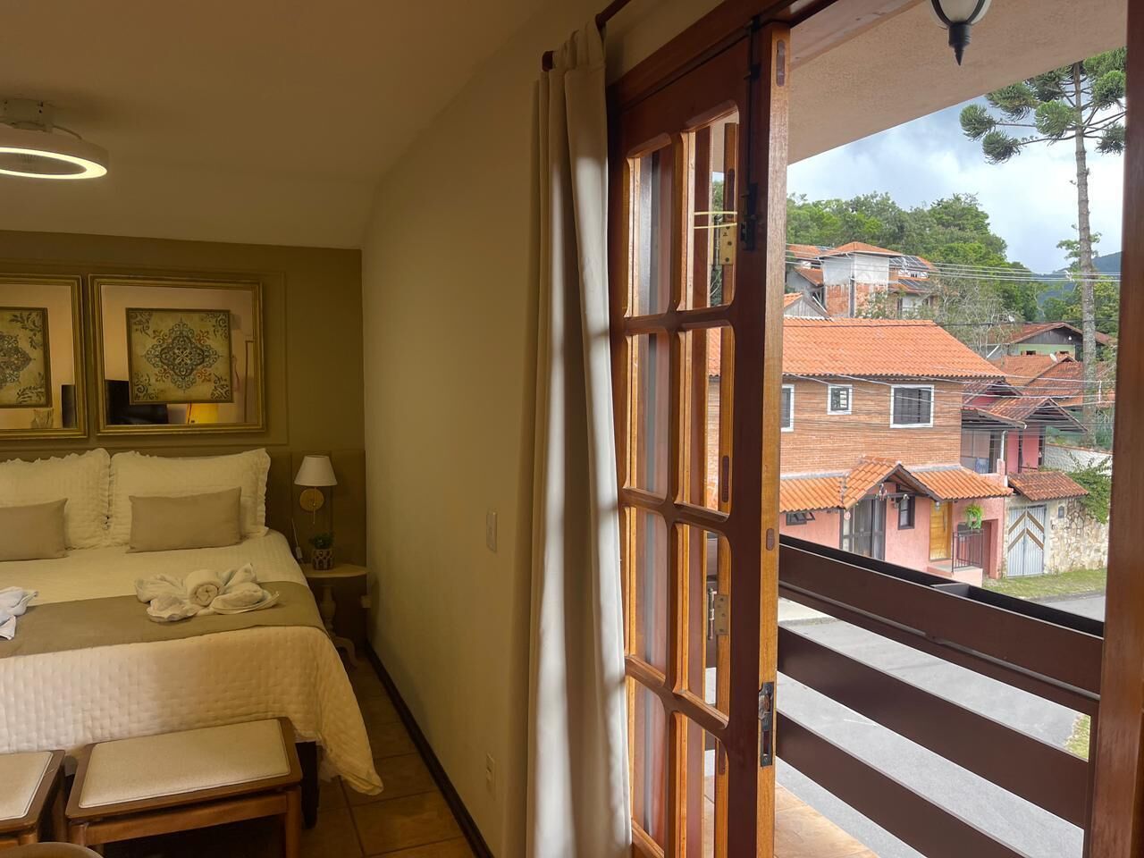 A bedroom with a bed, bedside table, and a view of the outside.