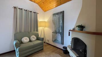 Un salón acogedor con un sofá verde, una lámpara de pie, una chimenea y un cuadro abstracto grande en la pared.