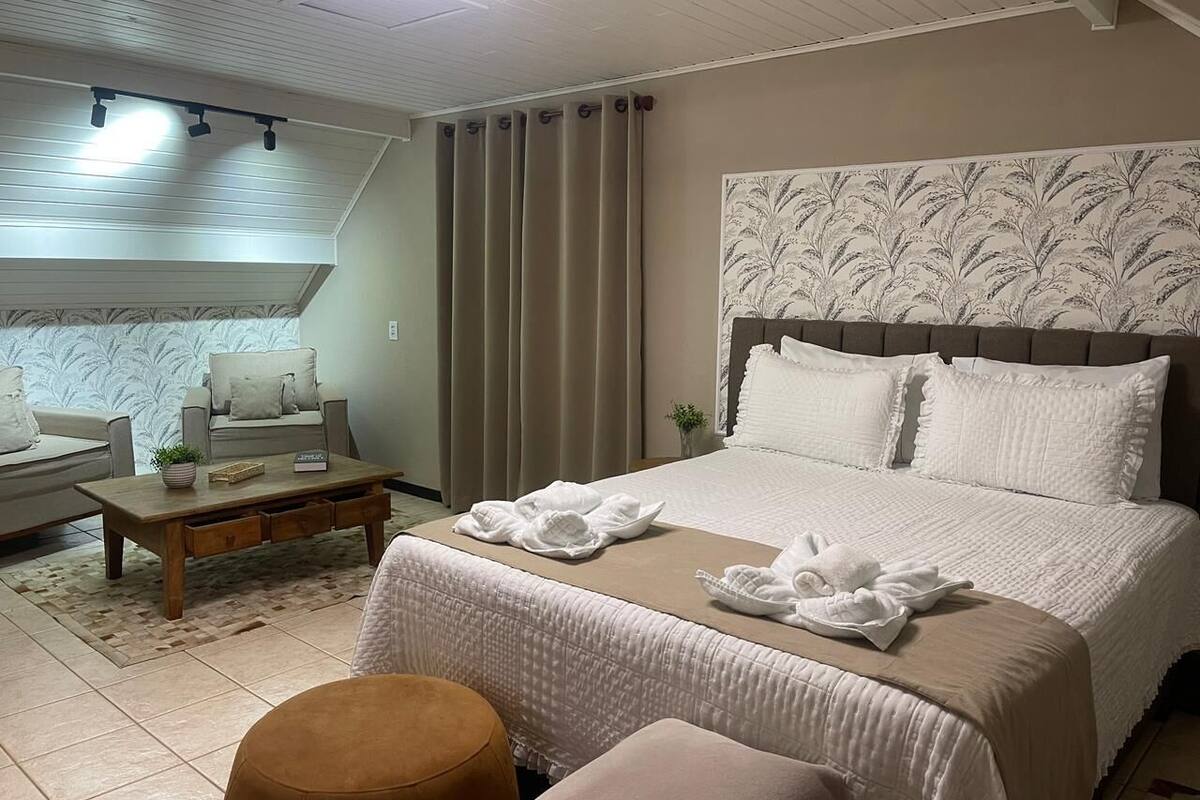 A hotel room with a bed, a sofa, a coffee table, and a small table with a plant.