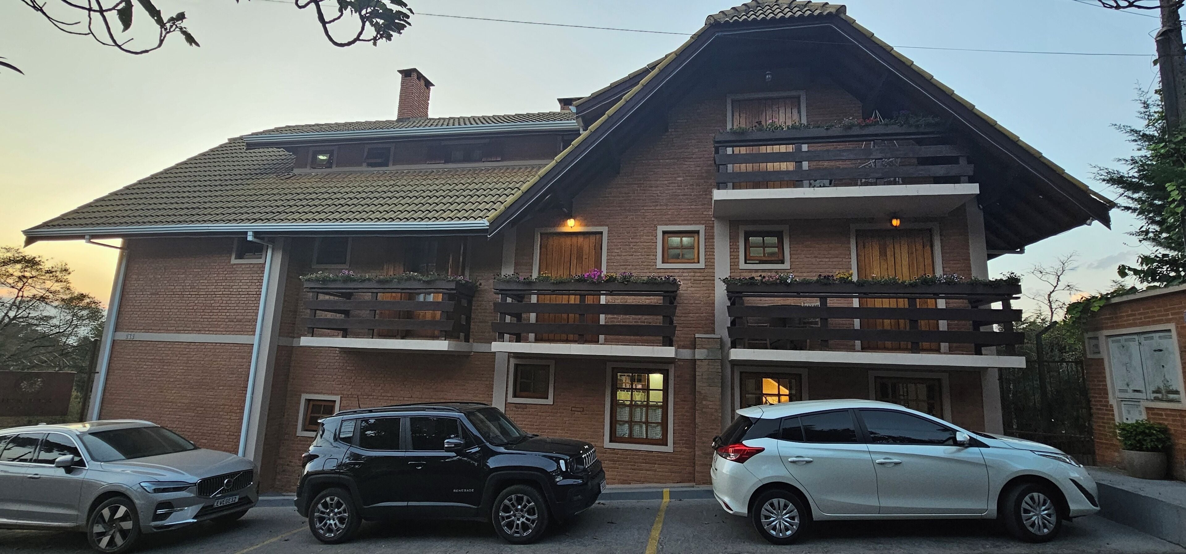 Un bâtiment à deux étages, doté d’une façade en briques, de balcons en bois et d’un toit recouvert de tuiles.