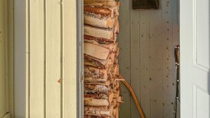 Ein schmaler Korridor mit einem Holzstoß und einem Metallbecken an der Wand.