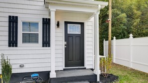 A house with a dark front door, white siding, and a small porch. - Stunning Charlotte Retreat ~ 2 Mi to City Center! (Charlotte)