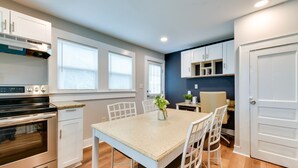 A modern kitchen with white cabinetry, a built-in oven, and a dining area with a table and chairs. - Stunning Charlotte Retreat ~ 2 Mi to City Center! (Charlotte)