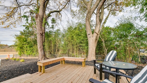 A wooden deck with a bench and a table with striped cushions. - Stunning Charlotte Retreat ~ 2 Mi to City Center! (Charlotte)