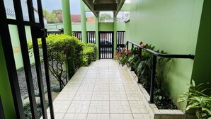 A covered walkway with a tiled floor, green walls, and a black gate. - The Rainier Bed & breakfast  (San José)