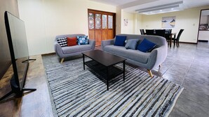 A modern living room with two grey sofas, a coffee table, and a TV. - The Rainier Bed & breakfast  (San José)