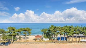 A coastal view with a beach, trees, a gazebo, and parked cars. - Baradeon Bada Pension, Yangyang (Yangyang)