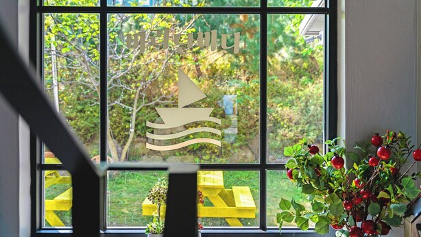 A window with a sailboat design, a yellow bench outside, and a potted plant with red berries. - Baradeon Bada Pension, Yangyang (Yangyang)