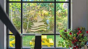 A window with a sailboat design, a yellow bench outside, and a potted plant with red berries. - Baradeon Bada Pension, Yangyang (Yangyang)