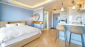 A modern hotel room with a large bed, a small kitchenette, and a bathroom visible through an open door. - Baradeon Bada Pension, Yangyang (Yangyang)