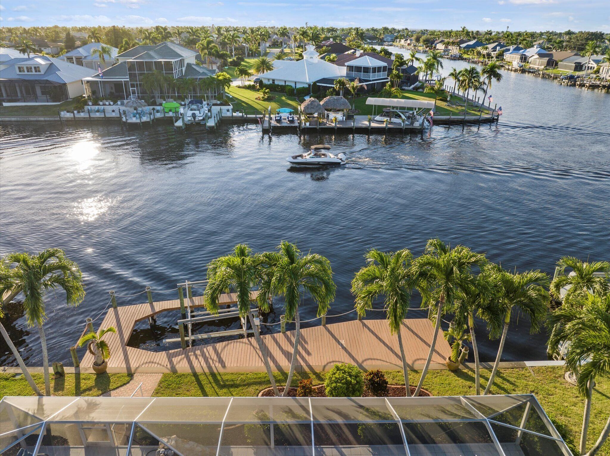 A waterfront property with a dock, boats, and a view of the surrounding neighborhood.
