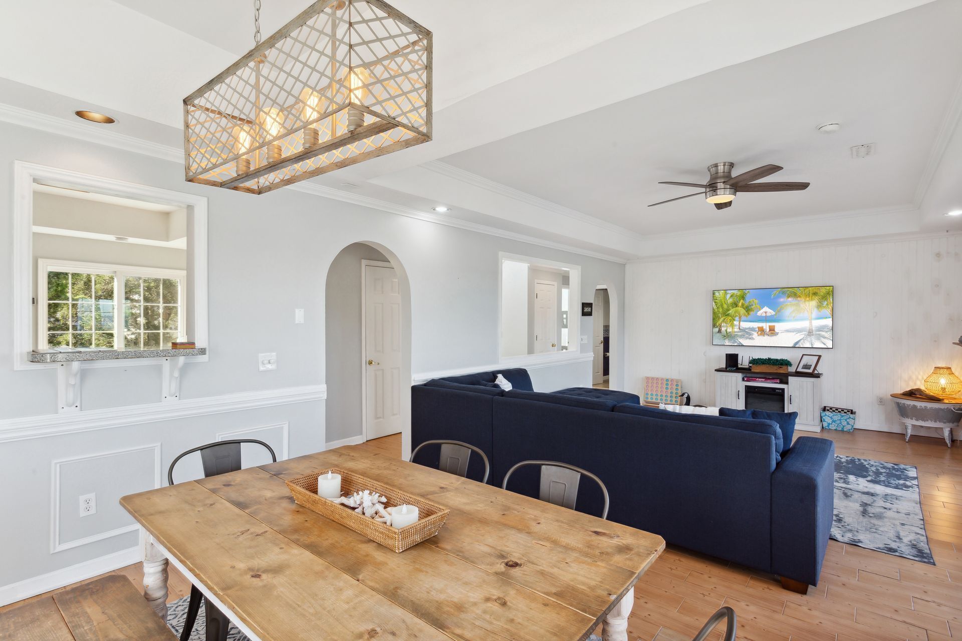 Un salon moderne avec une table à manger en bois, des canapés bleu foncé et un ventilateur de plafond.