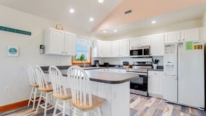 A kitchen with white cabinets, a central island with bar stools, a microwave, an oven, and a refrigerator. - 4 br, loft, dog friendly, pool firepit! (Avon)