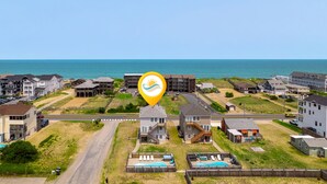 Una zona residenziale sul lungomare, con diverse case a due piani, una piscina e vista sull'oceano.