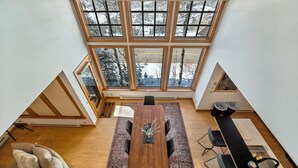 A spacious room with a large skylight, a wooden dining table, and a cozy seating area. - Ski in/Ski Out to Snowbird in Gorgeous Unit with Hot Tub and Beautiful Views (Alta)