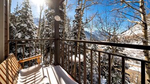 A balcony with a wooden bench, metal railing, and a view of snow-covered trees and mountains. - Ski in/Ski Out to Snowbird in Gorgeous Unit with Hot Tub and Beautiful Views (Alta)