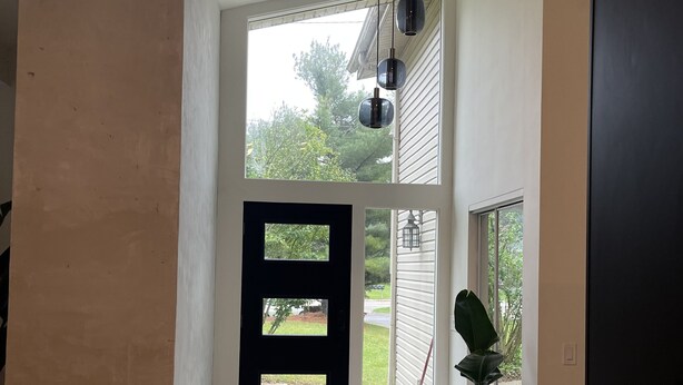 A modern entryway with a black door, a potted plant, and a view of the outside. - Minimalist sauna retreat  (Brighton)